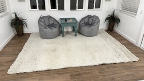 A room with two grey bean bag chairs, a small green table, and a white shag rug. - Cookies Cottage , 3 bedroom 2 bath cottage (Inglis)