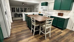 A modern kitchen with green cabinets, a wooden dining table, and a white refrigerator. - Cookies Cottage , 3 bedroom 2 bath cottage (Inglis)