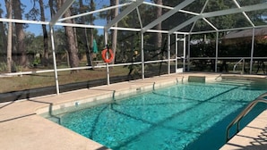 A swimming pool with a covered area, surrounded by trees.