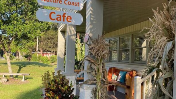 Une véranda avec une enseigne indiquant la présence d’un café et d’une zone naturelle en bord de mer.