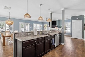 A spacious kitchen with dark cabinetry, a granite countertop, and pendant lighting. - Sojourn Baycation 4 BR House 5 Min walk to Beach (Norfolk)