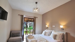 Un dormitorio con cama, mesitas de noche, televisor y vistas al exterior.