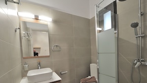 Un baño moderno con cabina de ducha de vidrio, un lavamanos blanco y un inodoro.