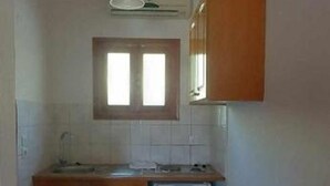 Una cocina pequeña con armarios de madera, un refrigerador blanco y una ventana sobre el fregadero.