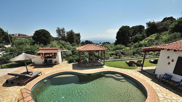 Una piscina con solárium empinado, dos gazebos y sillas de descanso.