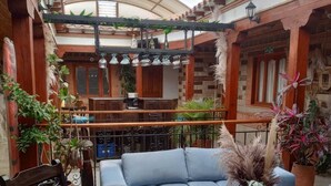 Un patio intérieur accueillant, avec un canapé bleu, une chaise en bois et une table agrémentée d’objets décoratifs.