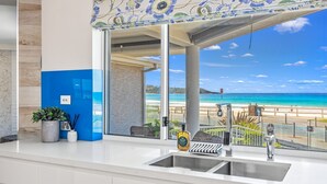 Eine moderne Küche mit einem großen Fenster mit Blick auf einen Strand.