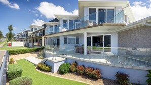 Ein modernes Wohngebäude mit Glasbalkon, gepflegtem Rasen und freiem Blick auf die umliegende Nachbarschaft.