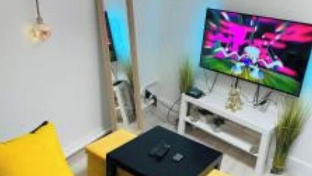 A modern living room with a flat-screen TV, a sofa, a coffee table, and a small side table. - renovated studio 30m2 5 min from the train station (Bordeaux)