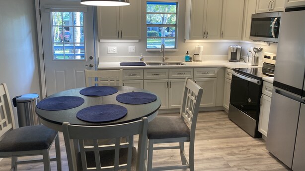 Una cocina moderna con armarios blancos, una estufa negra y una mesa de comedor con individuales azules.