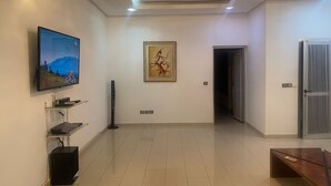 A spacious living area with a flat-screen TV, a framed artwork, and a door leading to another room. - Residence Jireh  (Abidjan)