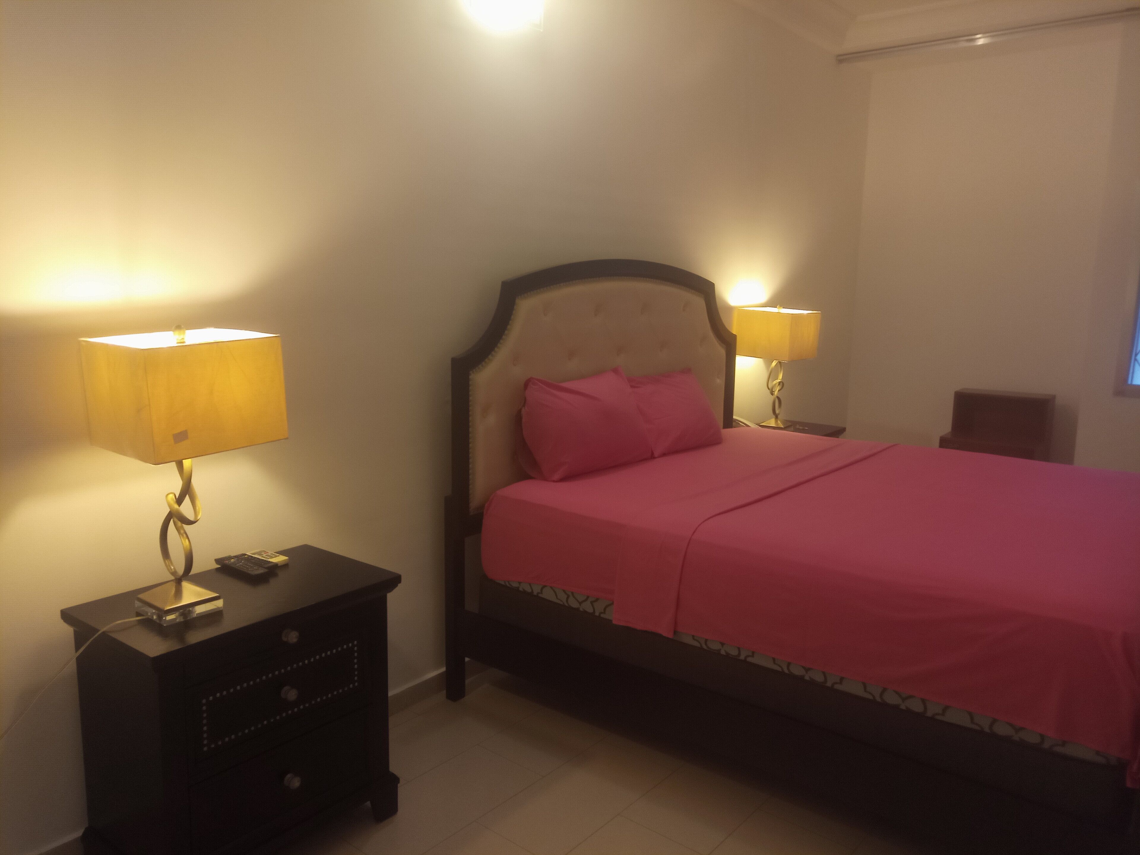 A bedroom with a bed, two bedside tables, and two lamps.