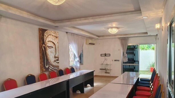 A conference room with a long table and chairs, a large wall painting, and a view through a glass door. - Residence Jireh  (Abidjan)