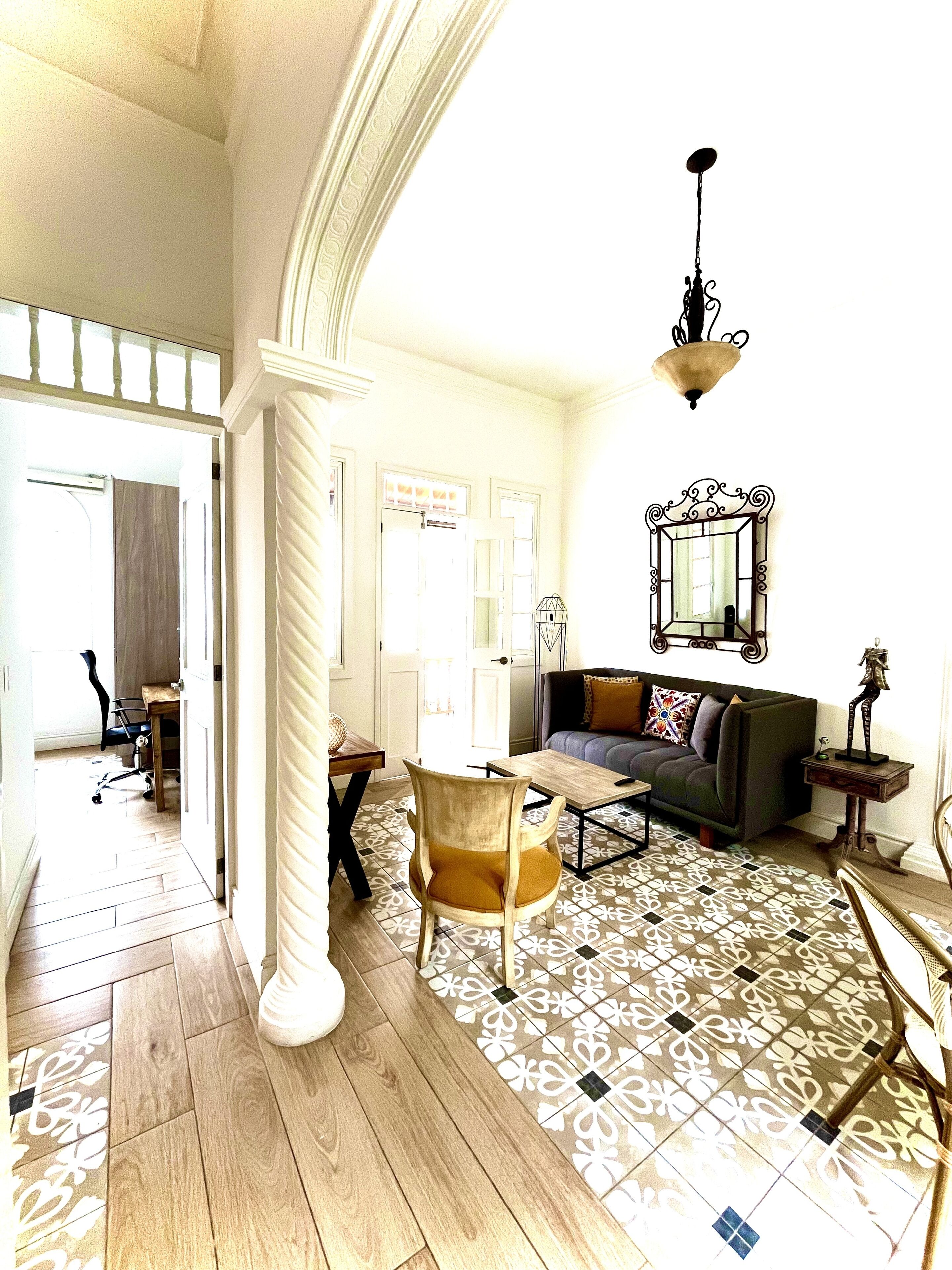 A spacious living room with a patterned floor, a sofa, a coffee table, and a chandelier.