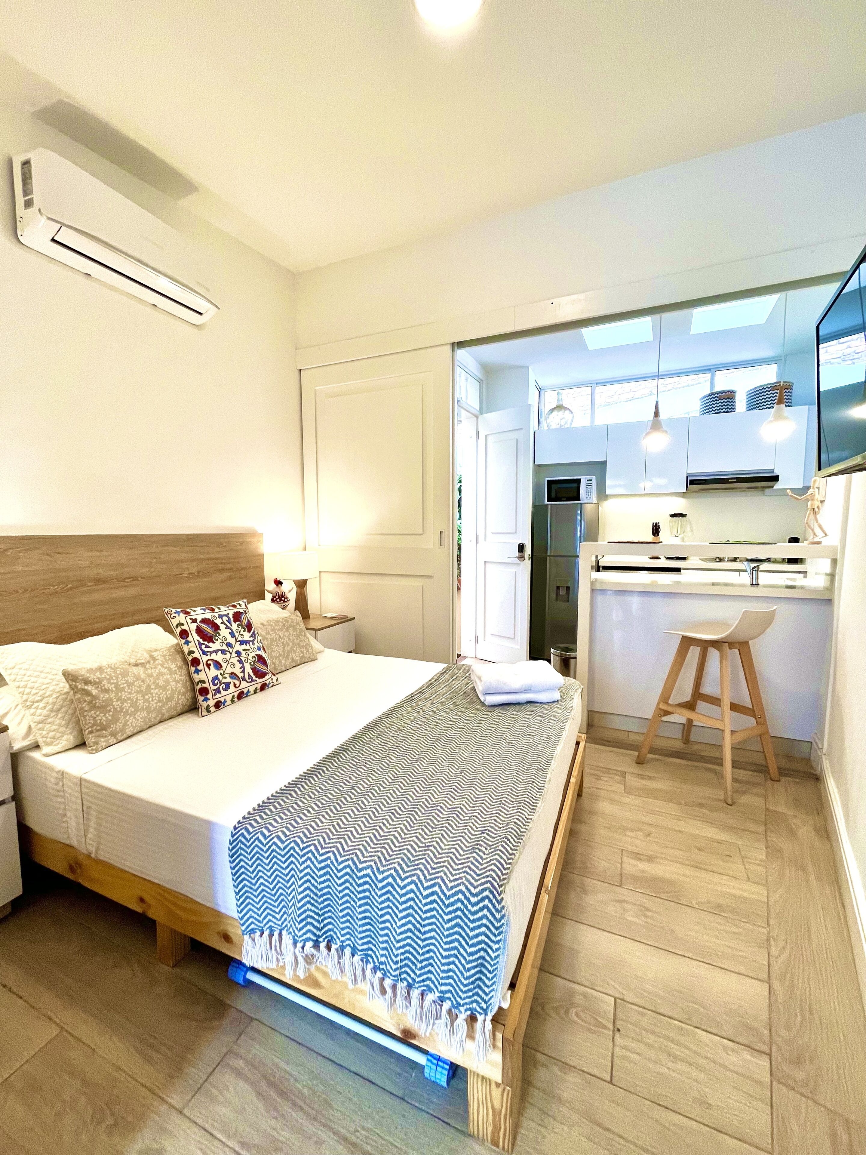 Un dormitorio con cama, mesita de noche y vistas a una zona de cocina.