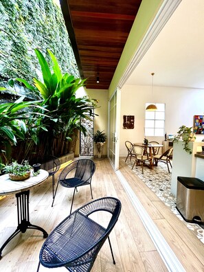 Un comedor con una mesa redonda y sillas, techo de madera y una pared con plantas.