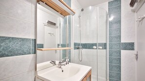 Une salle de bain moderne avec un lavabo blanc, un miroir et une cabine de douche.