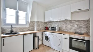 Une cuisine compacte équipée d’un évier, d’un four à micro-ondes, d’un lave-linge et d’un four.