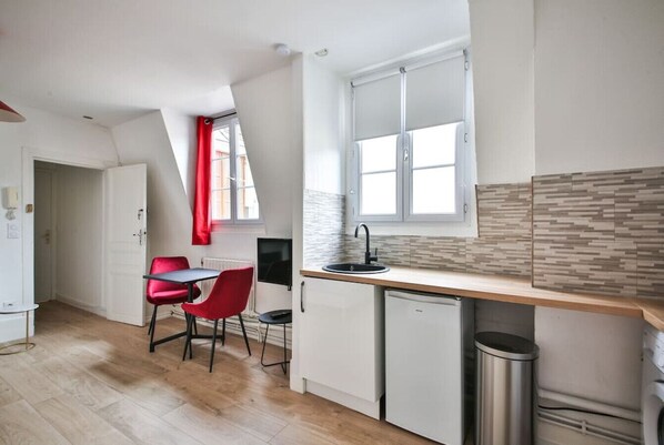 A compact kitchen with white cabinets, a small sink, and a compact dishwasher.