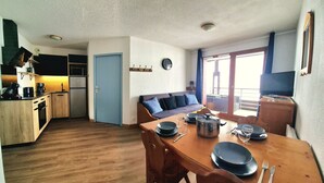 Een compacte leefruimte met een kitchenette, eethoek en een bank.