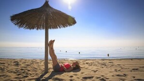A beach scene with a straw umbrella and a person lying on the sand. - Rêve de plage - Confortable appt pour 2 (Canet-en-Roussillon)