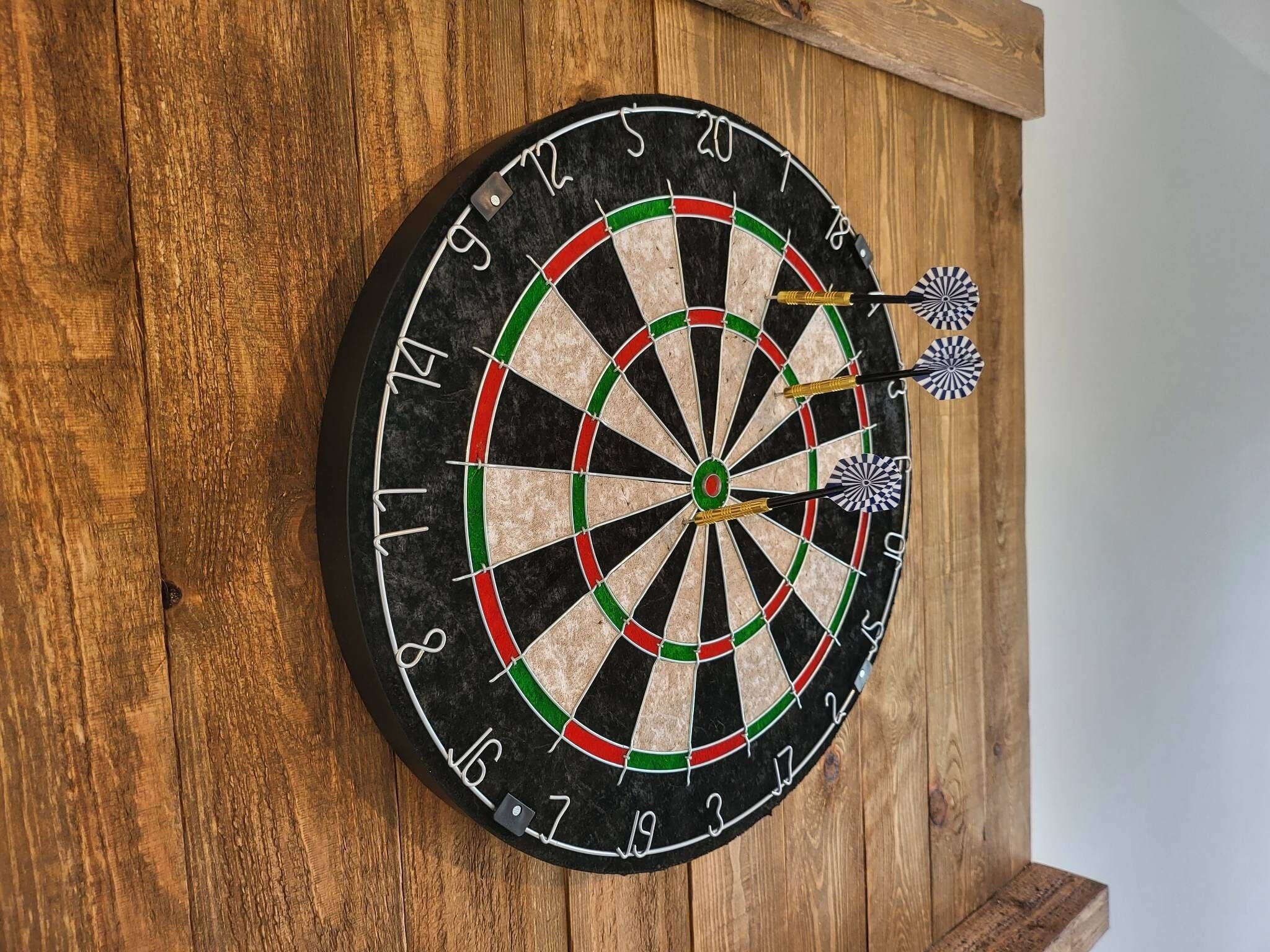 Une cible de fléchettes fixée à un mur en bois.