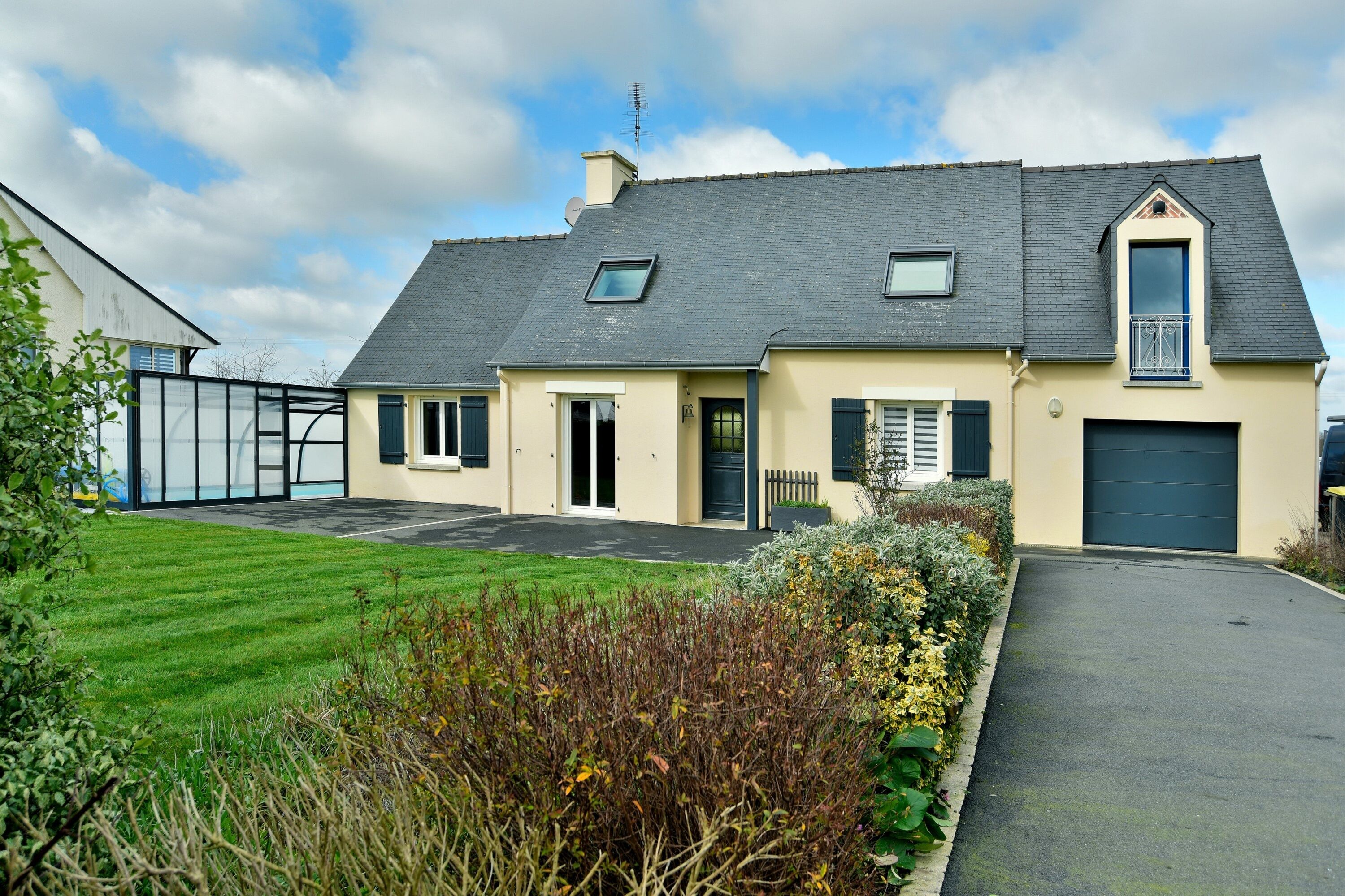 A two-story house with a grey roof, a garage, and a well-maintained lawn.