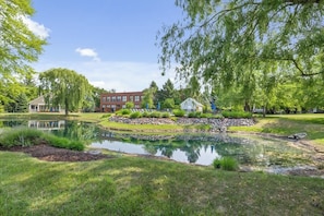 A tranquil park with a pond, a red building, and a white house.