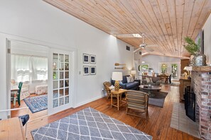 Cozy living area with a high ceiling, sofa set, coffee table, dining table, and fireplace.