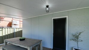 Un patio con una mesa y banco de madera, una planta en maceta y una puerta.