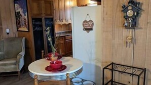 Una cocina acogedora con armarios de madera, un refrigerador, una mesa de comedor con platos rojos y una estantería para vinos.