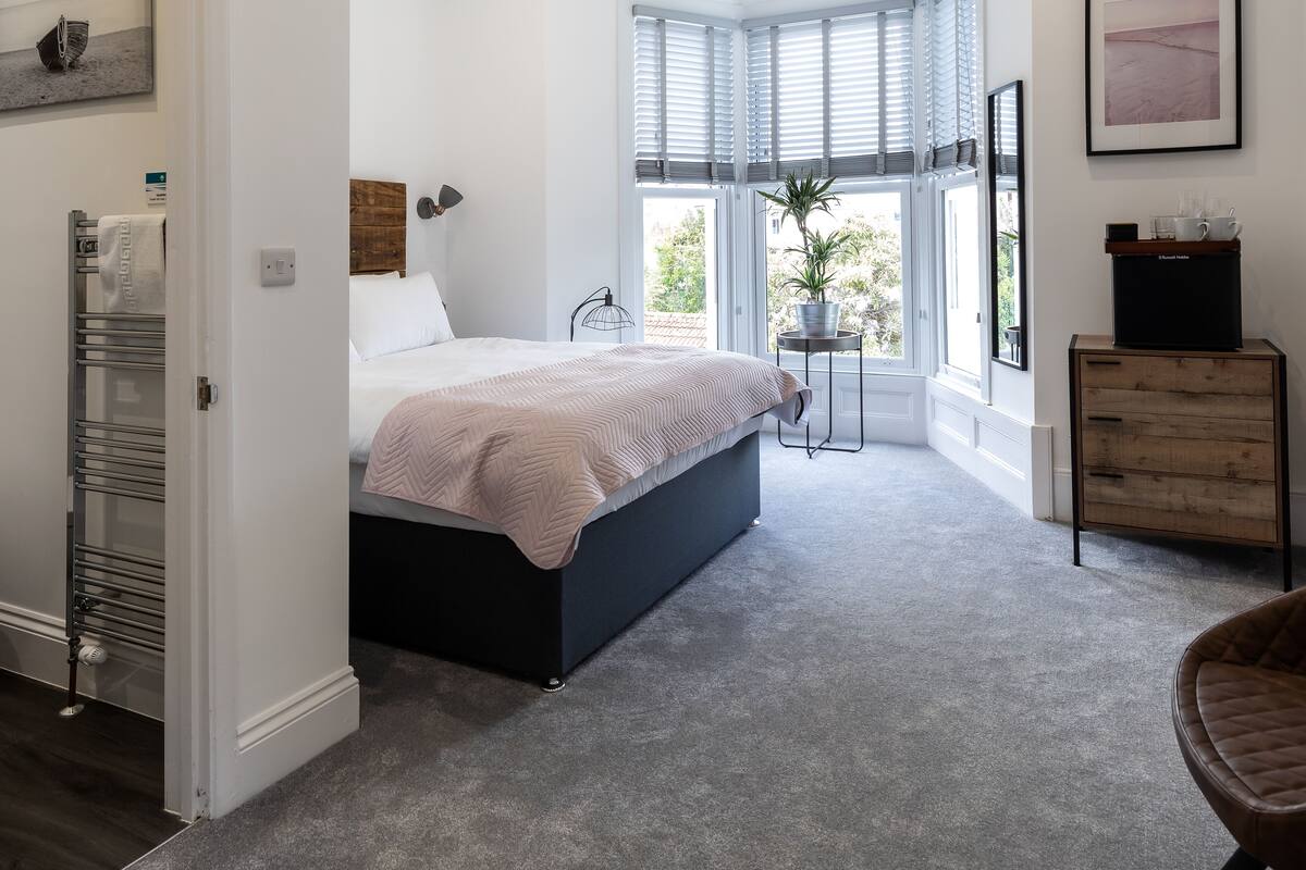 A modern bedroom with a bed, a side table, a chair, and a dresser.