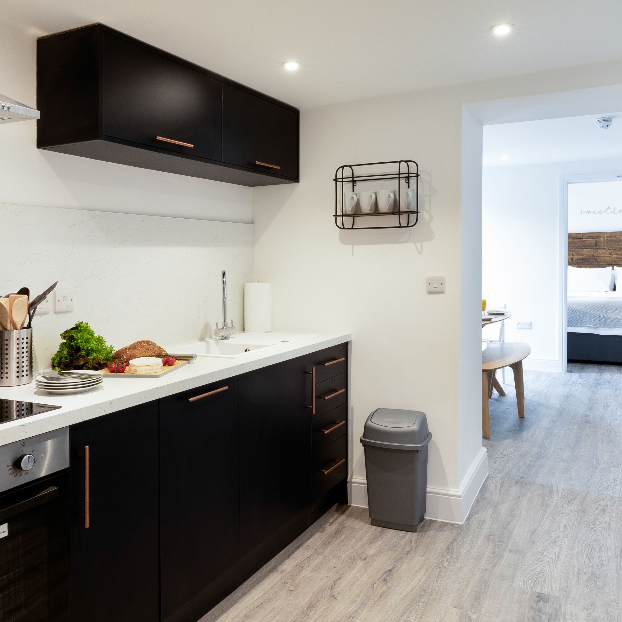 A modern kitchen with black cabinets, a white countertop, and a stainless steel range hood.