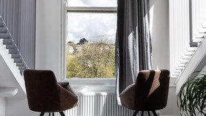 A room with a large window, two brown chairs, a radiator, and a plant. - Park View (Falmouth)