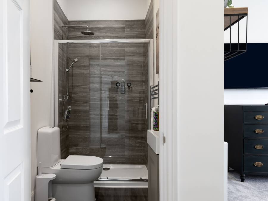 A modern bathroom with a glass-enclosed shower, a toilet, and a vanity with drawers.