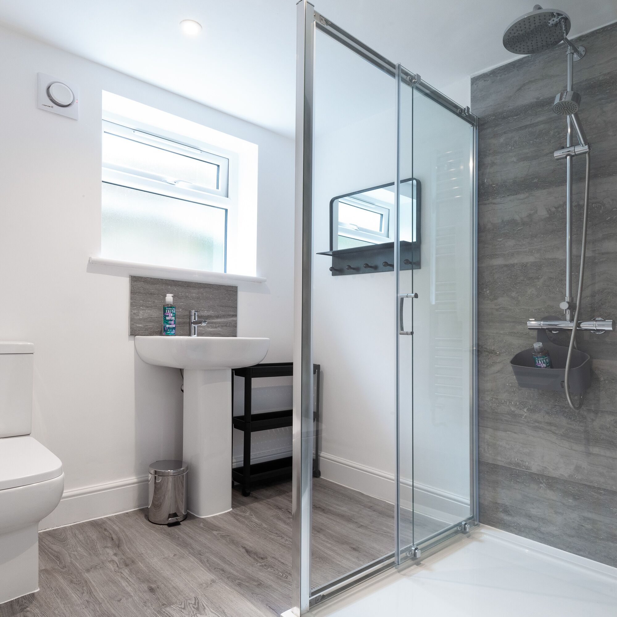 A modern bathroom with a glass shower enclosure, a white sink, and a toilet.