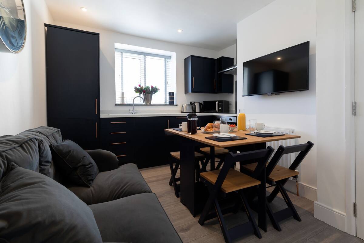 A compact living space with a kitchenette, a dining area with a table and chairs, and a sofa.