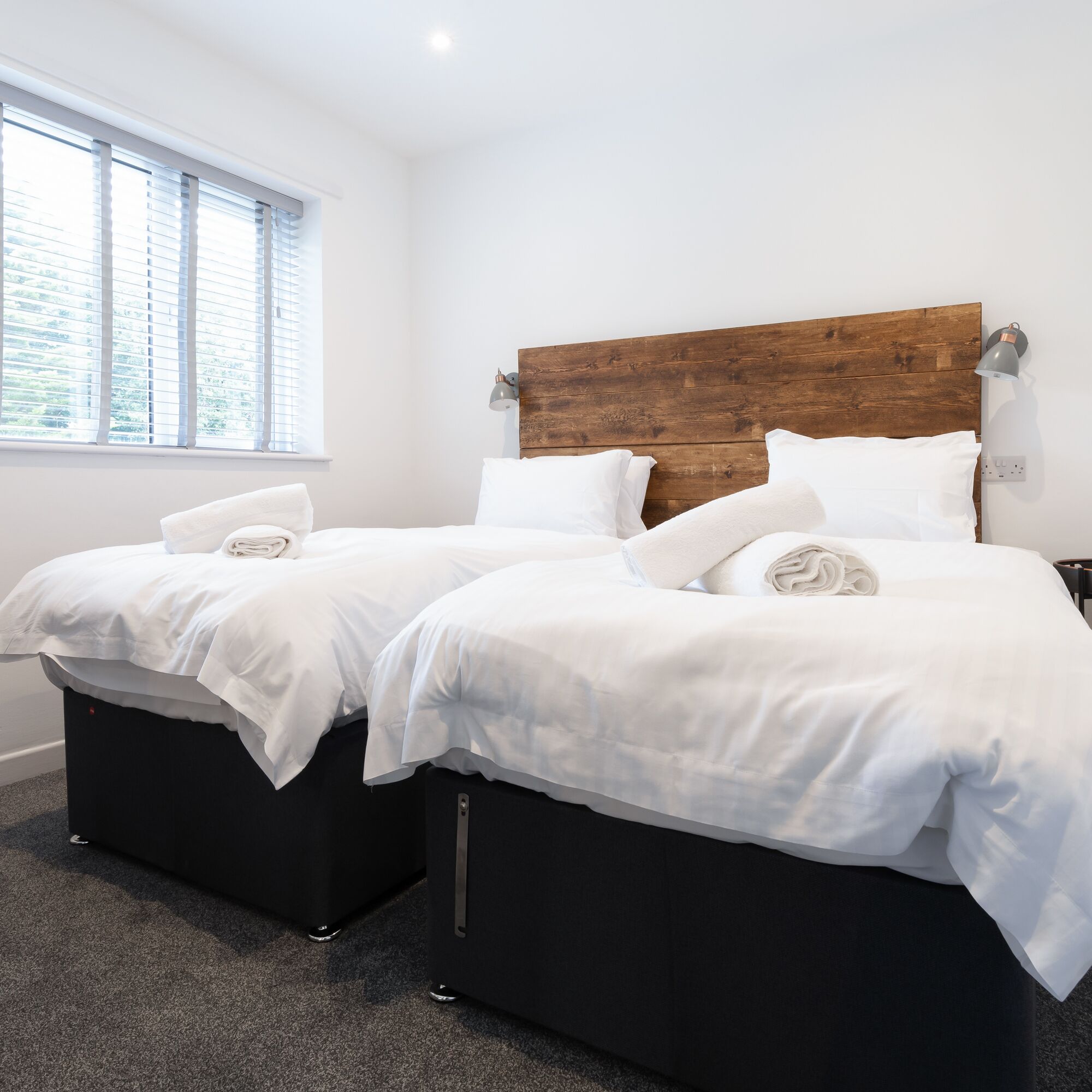 A double bed with white linens and a wooden headboard in a hotel room.