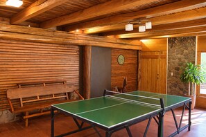 Una mesa de ping pong en una habitación con paredes de madera y una pared de acento de piedra.