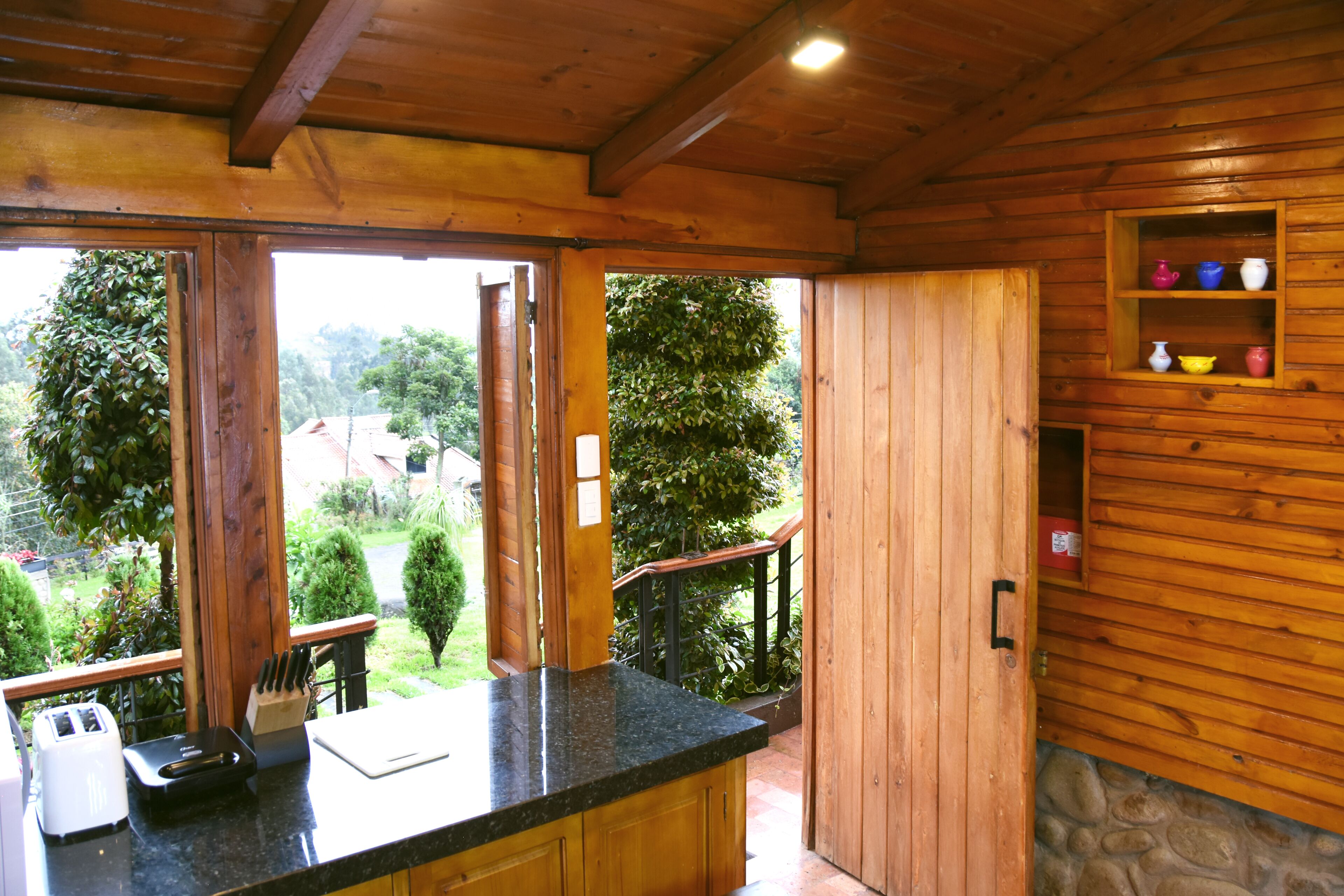 Interior de madera con cocina, que incluye una encimera, un tostador y un mueble con objetos de colores.