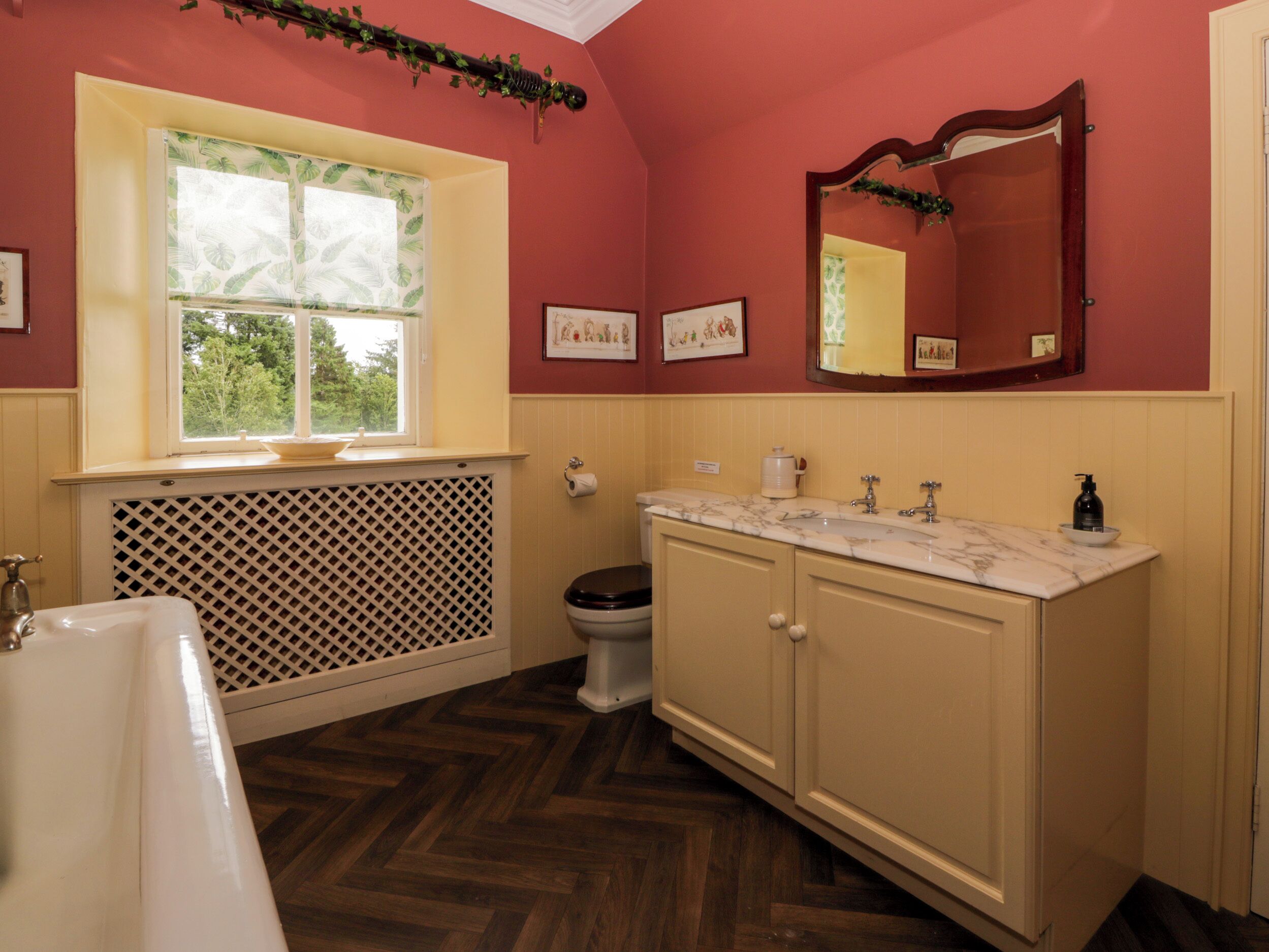 A bathroom with a bathtub, toilet, vanity with a mirror, and a window.