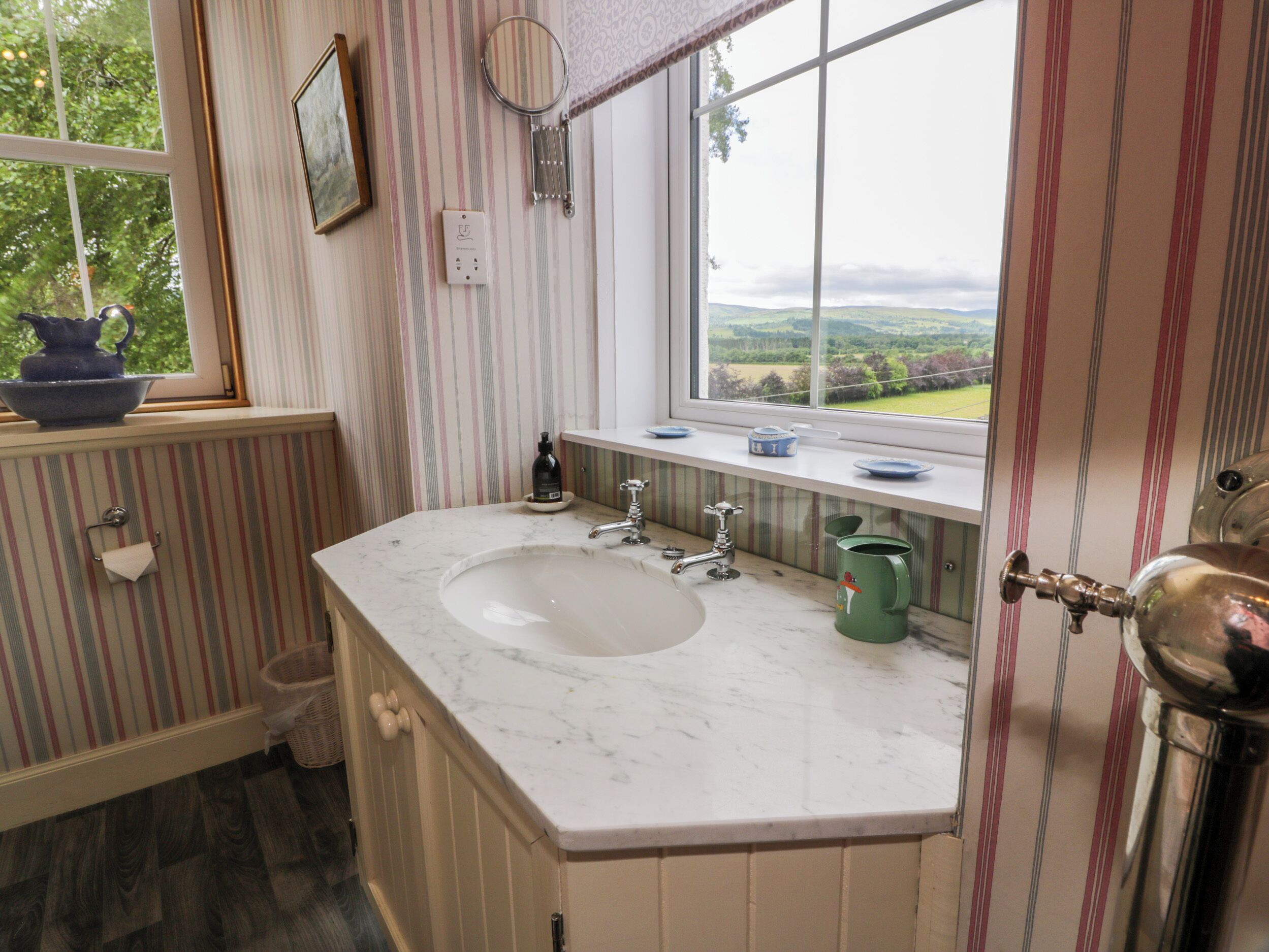 A bathroom with a large window, a sink, and a mirror.