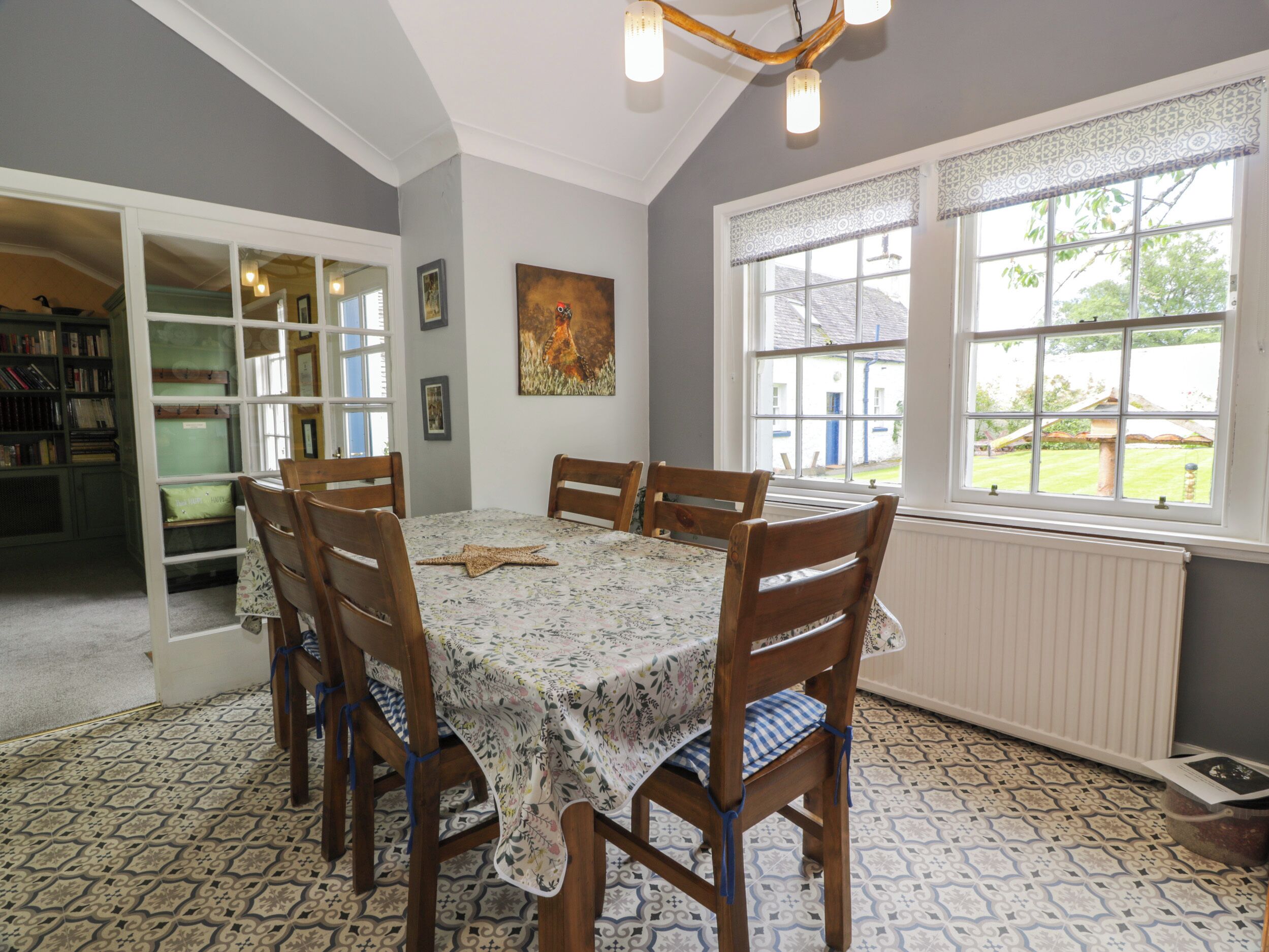 A dining area with a table set for four, surrounded by wooden chairs, a patterned tablecloth, and a starfish decoration.