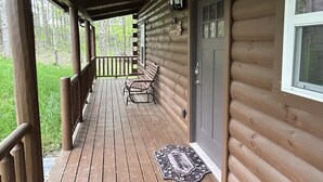 Eine Holzhütte mit Veranda, einer Bank und einer Fußmatte.
