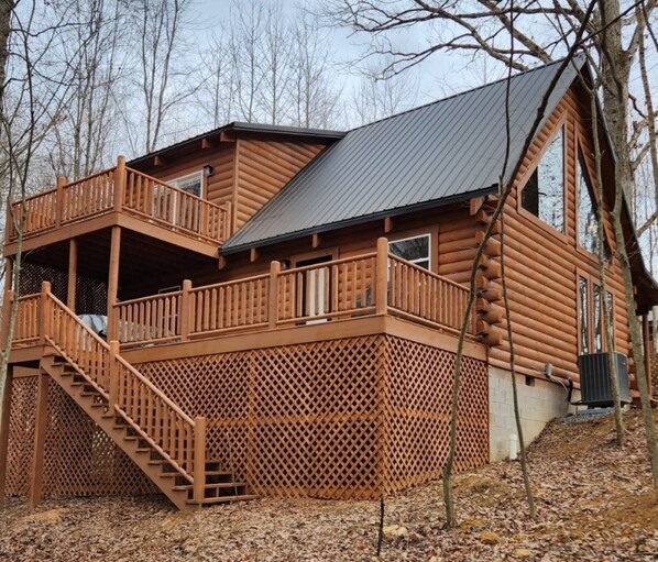 A log cabin with a balcony and a staircase leading to an upper level.