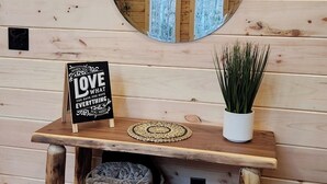 Una panchina in legno con uno specchio, un cartello e una pianta, sullo sfondo di un muro in legno.