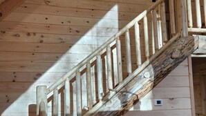 Una scala in legno dal design rustico che conduce a una stanza con un tavolo rotondo e una sedia.