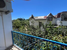 Ein Wohngebäude mit weißer Fassade, rotem Dach und einem blauen Balkongeländer.