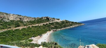 Eine Küstenlandschaft mit Strand, steinigen Klippen und blauem Meer.