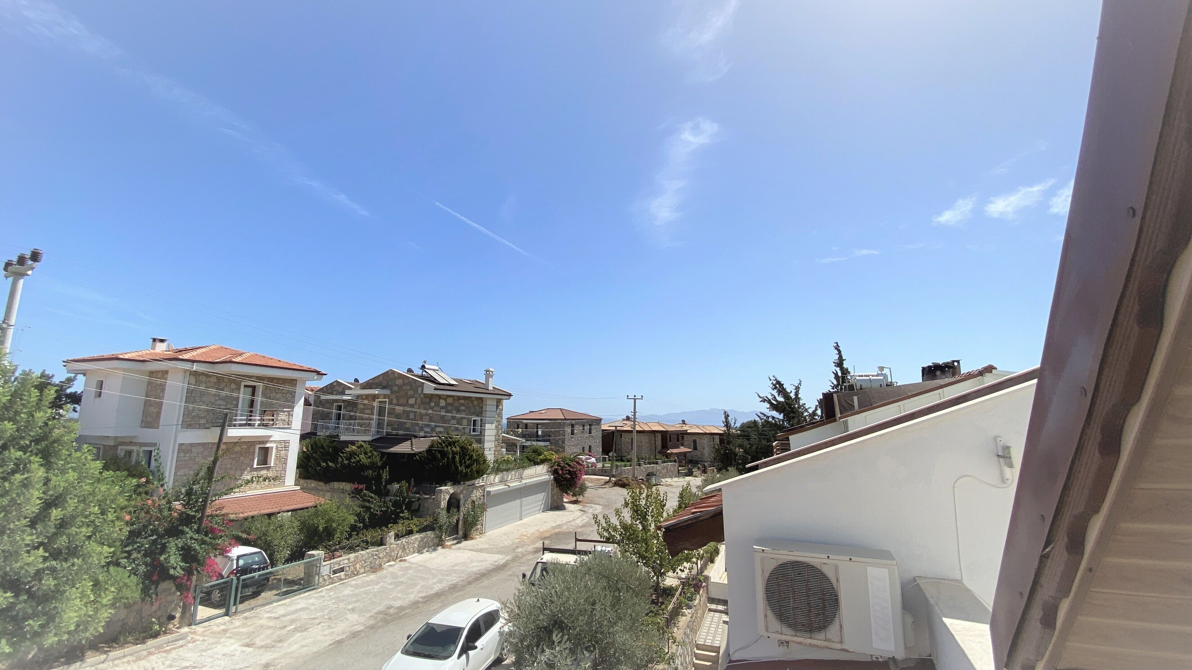 A residential area with stone buildings, a clear sky, and a white car parked on the street.